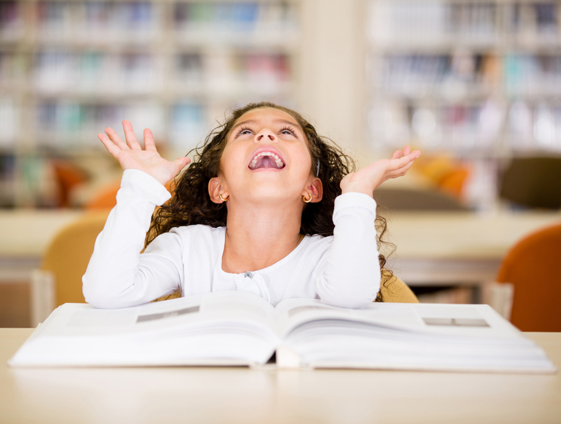 Young girl in the library with a textbook